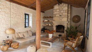 A cozy room with a stone fireplace, wooden furniture, and a comfortable seating area. - GAIA Alacati (Cesme)