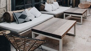 An outdoor seating area with a sofa, two tables, and wicker chairs. - GAIA Alacati (Cesme)