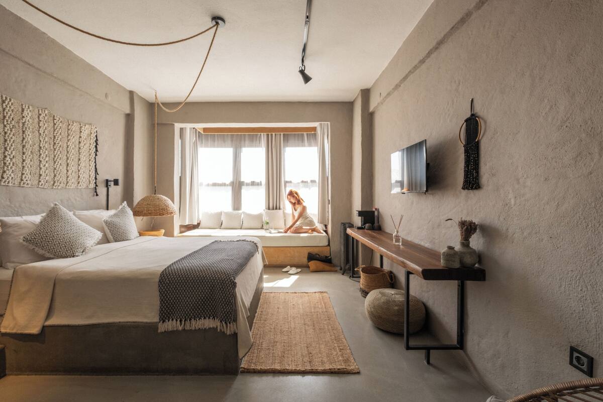Un dormitorio moderno con cama, mesita de noche y un ventanal grande.
