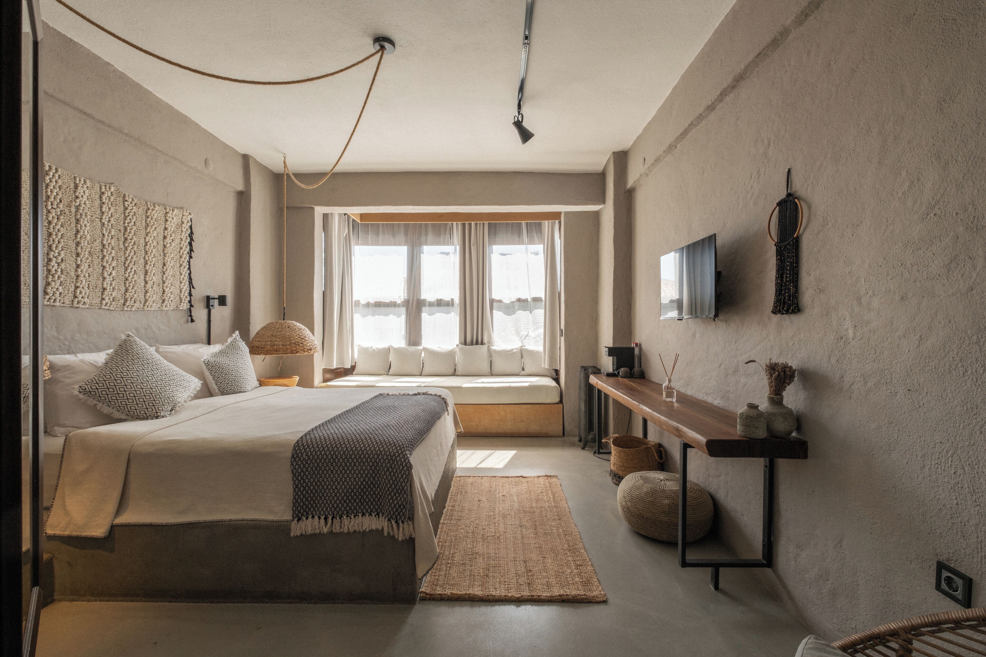 A modern bedroom with a bed, bedside tables, a TV, and a view of the outdoors.