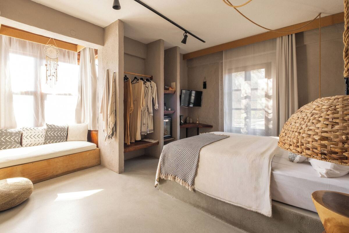 Un dormitorio moderno con cama, zona de estar, televisor y armario.