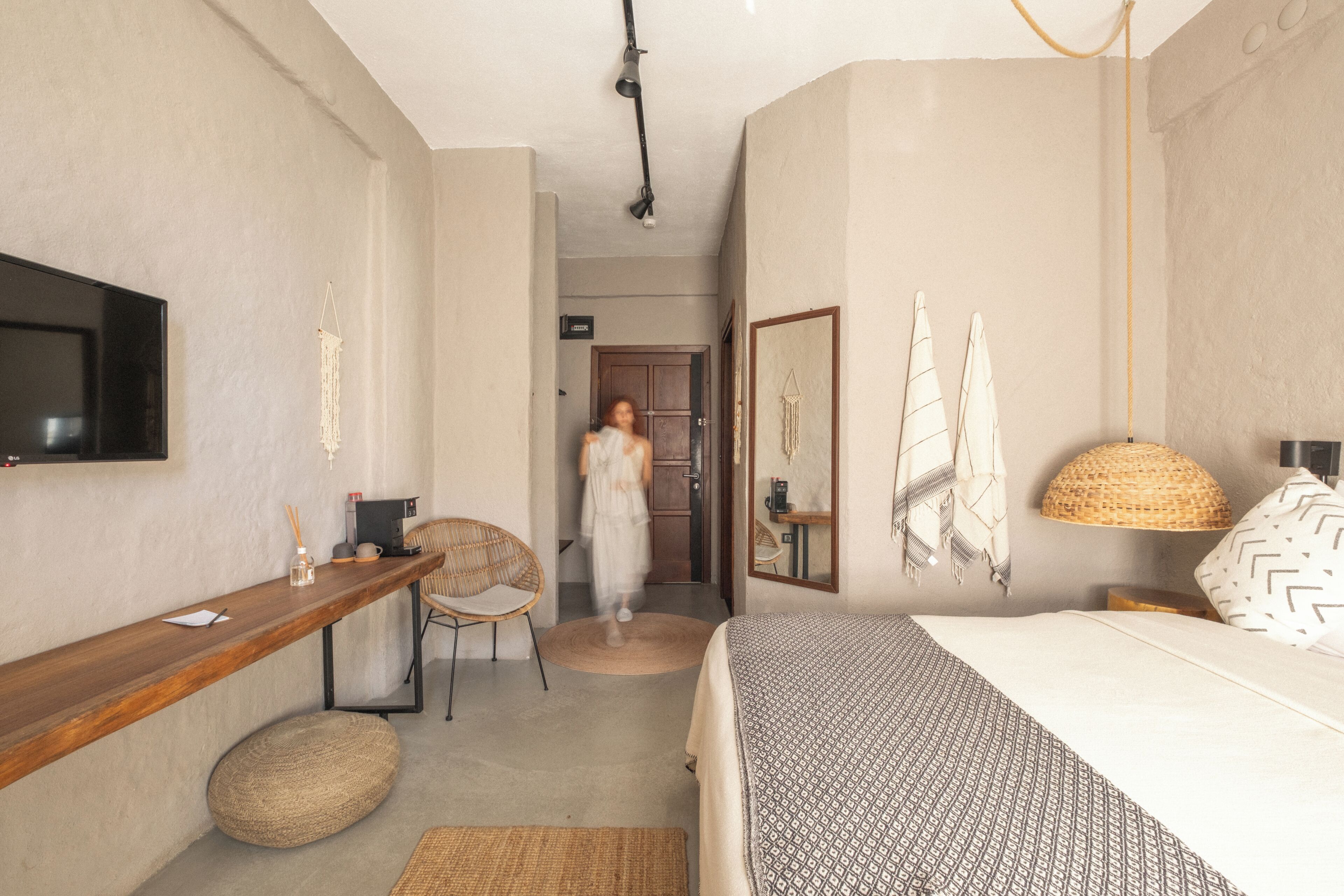 Hotelkamer met een bed, een bureau, een stoel, een televisie en een gang naar een deur.