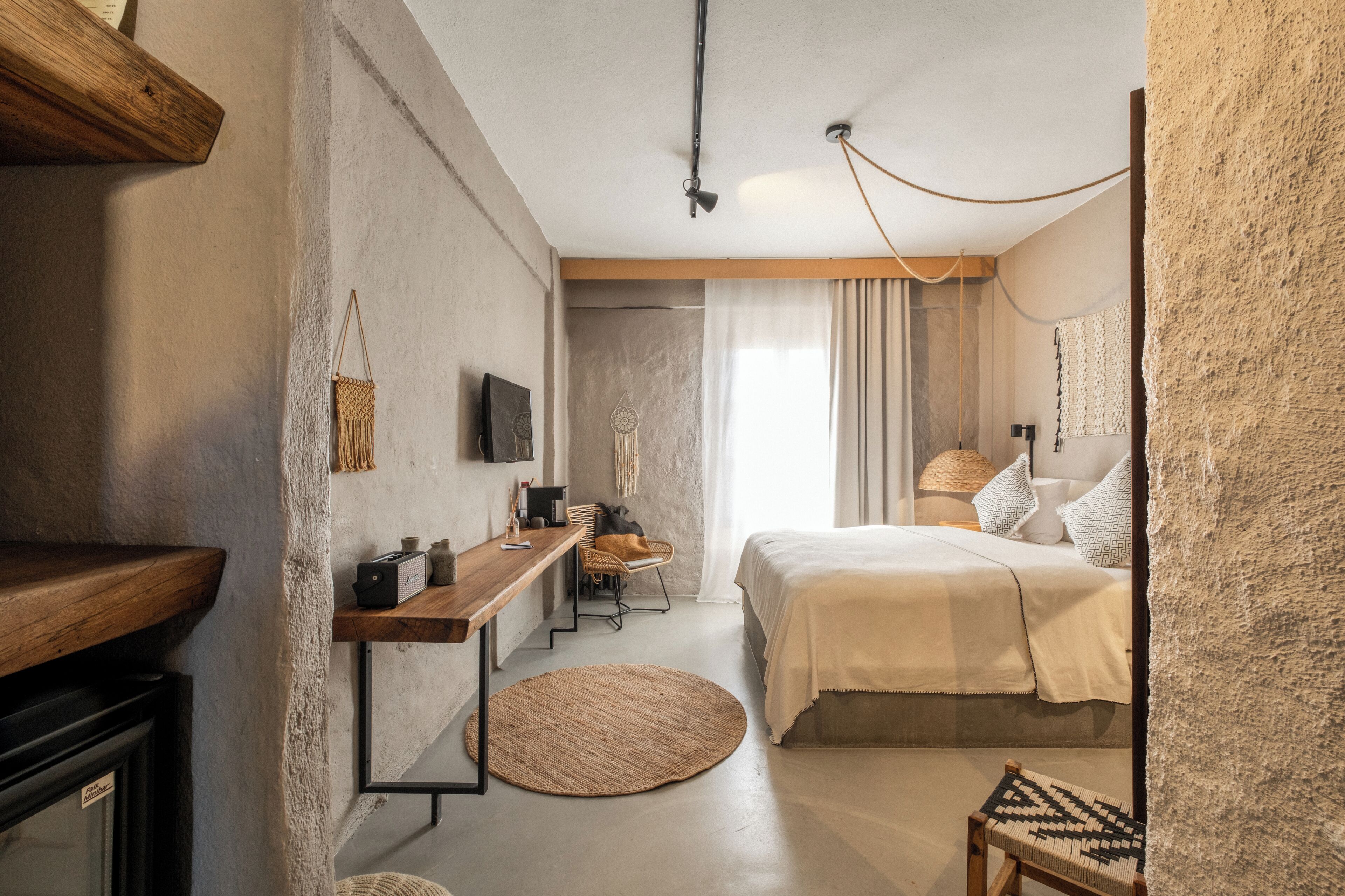 A bedroom with a bed, bedside table, lamp, and a round woven rug.
