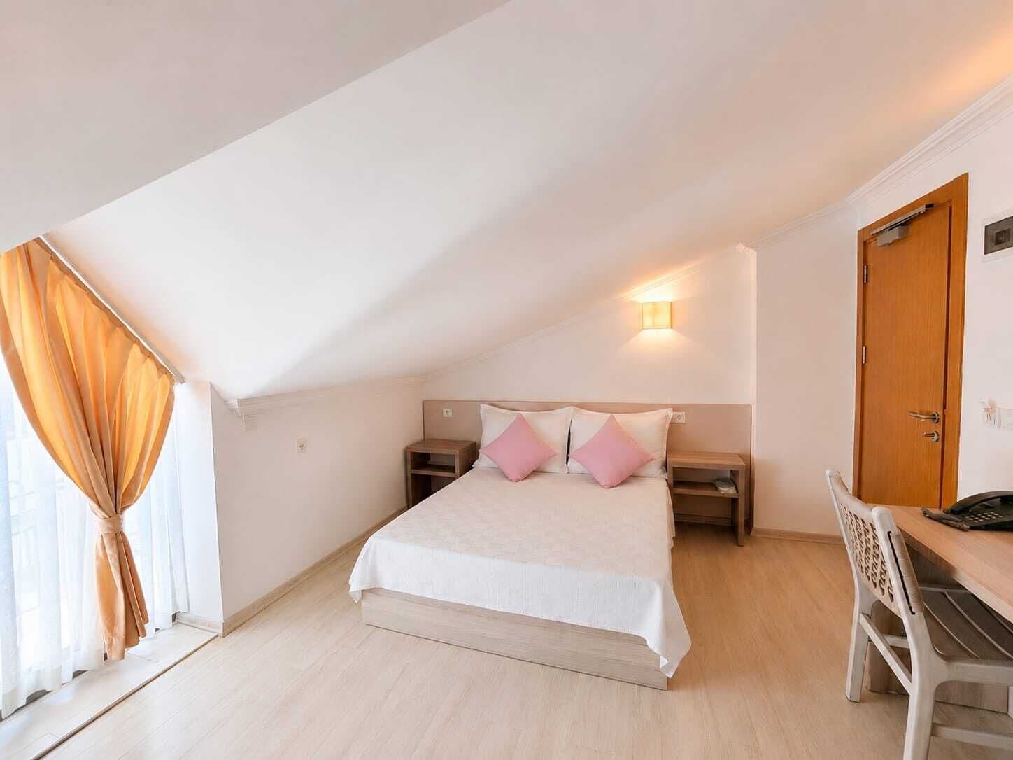 A bedroom with a bed, bedside tables, a desk, and a chair.