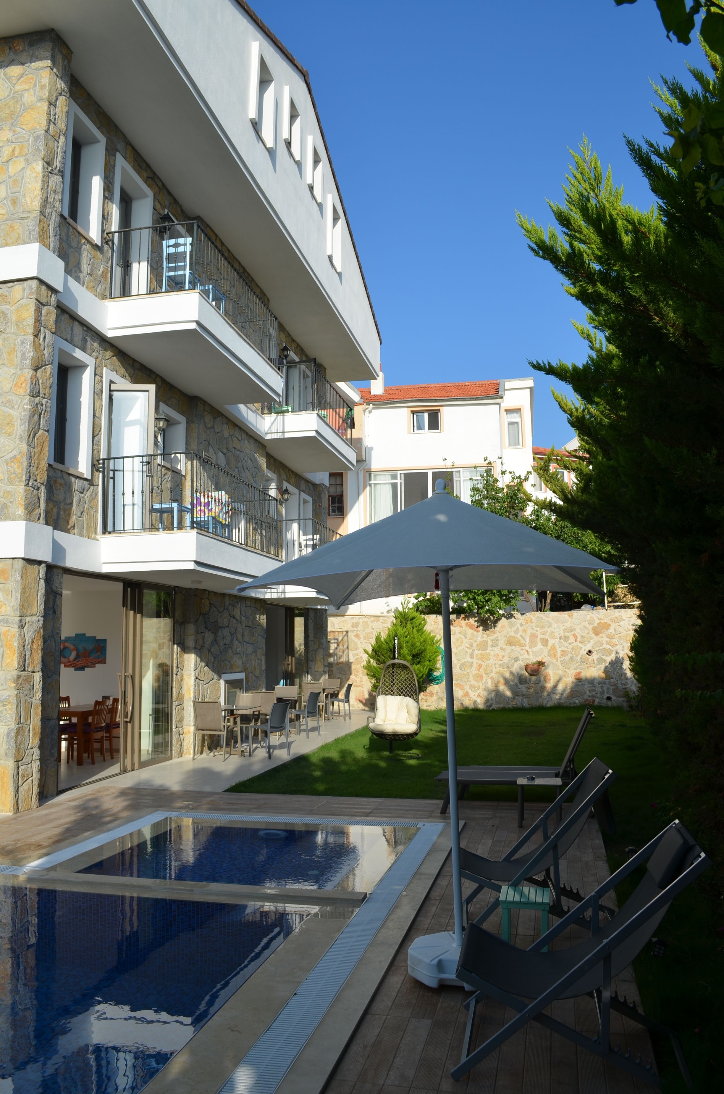 Un edificio moderno con piscina, mobiliario exterior y fachada de piedra.