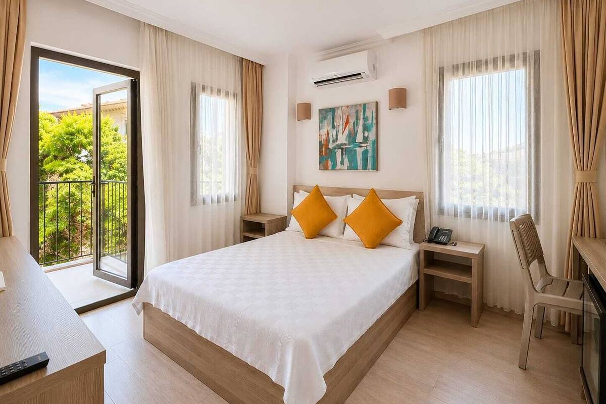 Ein Hotelzimmer mit Bett, Schreibtisch, Stuhl, einem Gemälde und einem Balkon mit Blick.