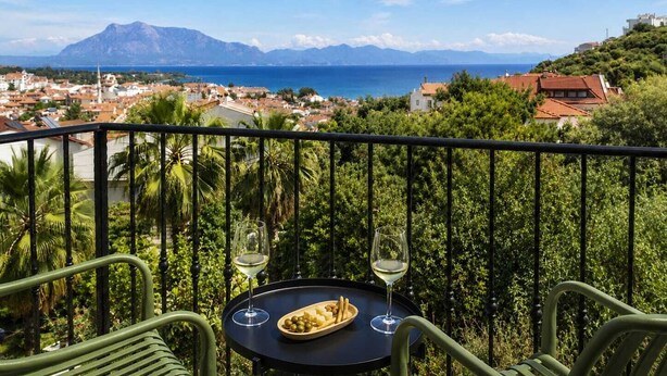A balcony with a table, two wine glasses, and a plate of olives. - Aria Doria Otel (Datça)