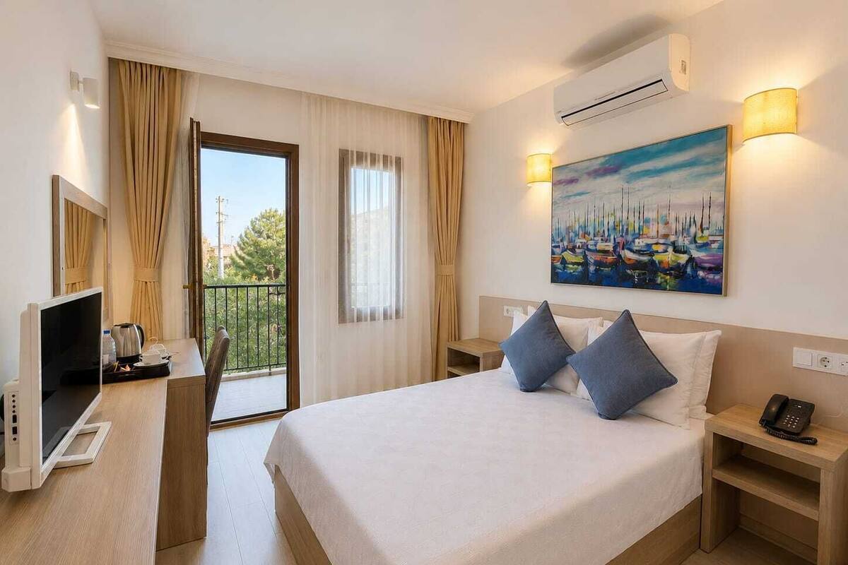 Ein Hotelzimmer mit einem Bett, einem Schreibtisch mit Fernseher, einem Gemälde und einer Klimaanlage.