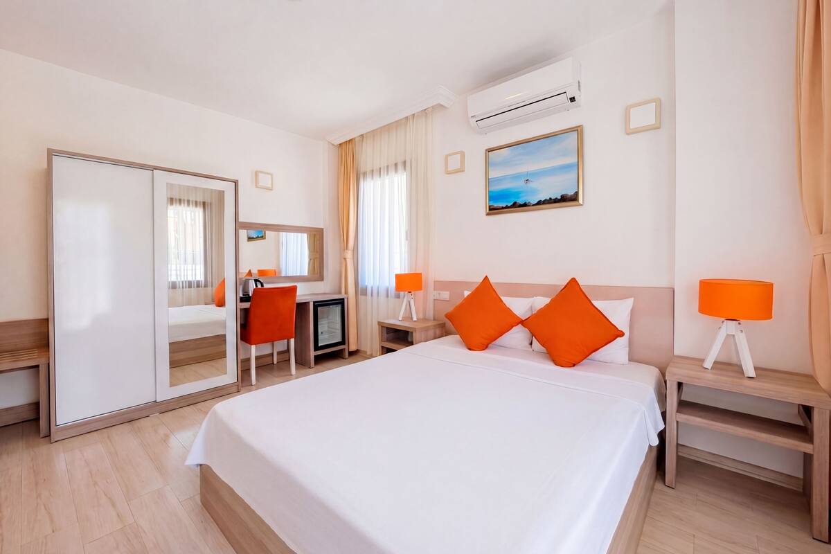 Ein Hotelzimmer mit einem Bett, einem Schreibtisch, einem Stuhl, einem Fernseher und einer Klimaanlage.