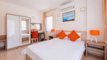 Habitación de hotel con cama, escritorio, silla, televisor y aire acondicionado.