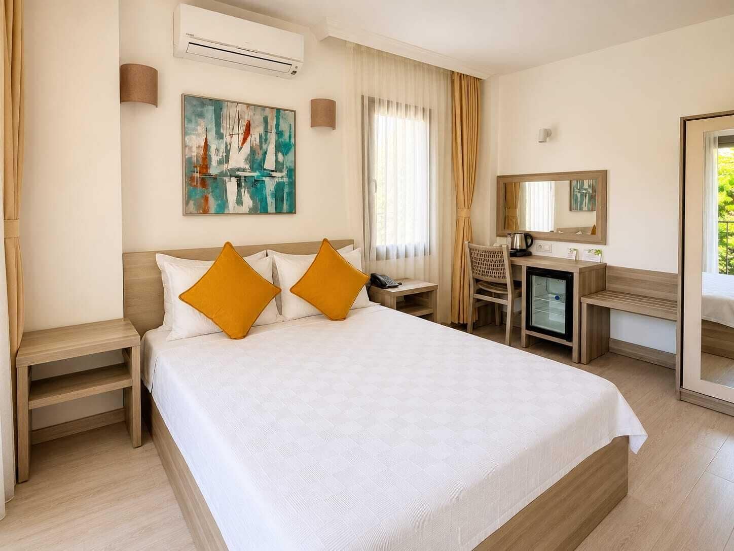 Une chambre d’hôtel avec un lit, un bureau, une chaise, un miroir et un tableau au mur.