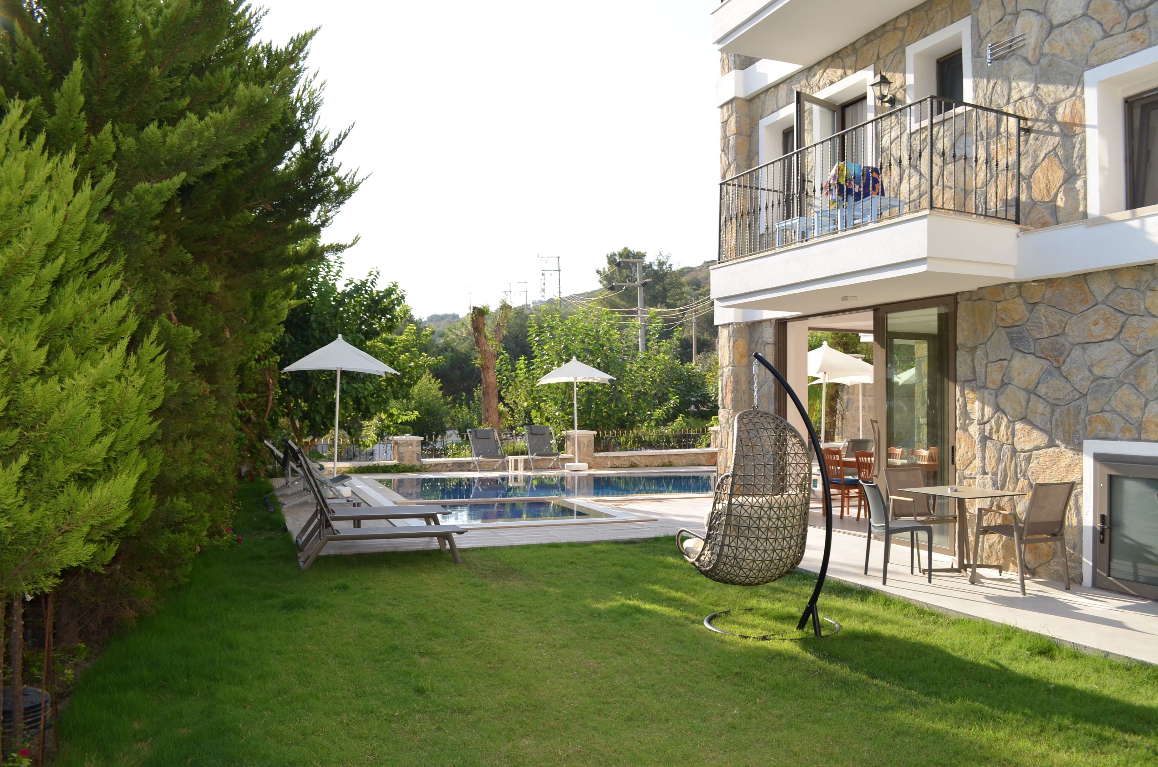 Ein modernes Haus mit Steinverkleidung, einem Swimmingpool, Sitzgelegenheiten im Freien und einem Hängesessel.
