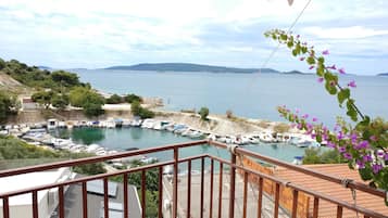 Un balcón con vistas a un puerto deportivo, barcos y una costa lejana.