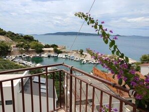 A balcony with a view of a marina, boats, and a distant coastline.