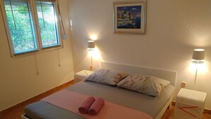 Una cama bien hecha con toallas rosadas, dos lámparas de noche y un cuadro en la pared.