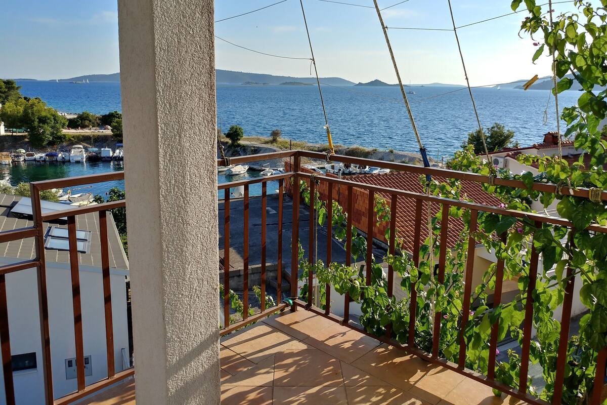 A balcony with a view of the sea, a tiled floor, and a railing.