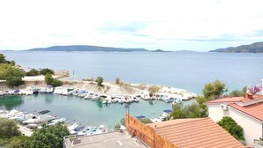Un puerto deportivo con barcos amarrados, cielo despejado y colinas al fondo.