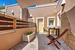 A patio with a wooden chair, a table, and a potted plant. - MiCasa (Santorini)