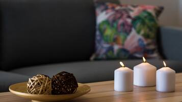 Una mesa de madera con tres velas blancas y dos bolas decorativas sobre un plato.