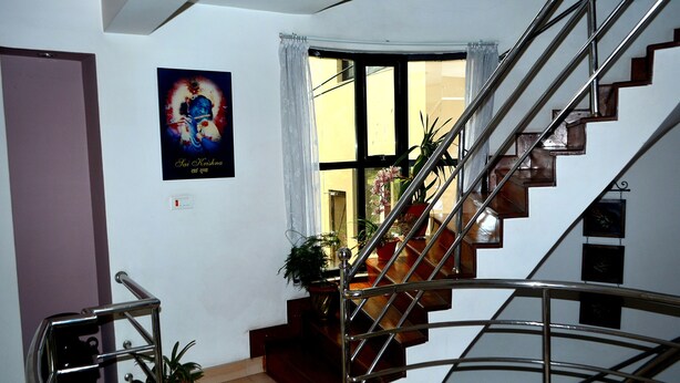 Una escalera con barandillas metálicas, un cartel en la pared y plantas en macetas.