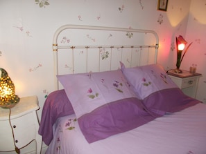 Cozy retreat with a white bed, floral wallpaper, and a bedside table.
