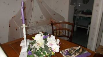 A dining table with a candle, a bouquet of flowers, and a magazine.