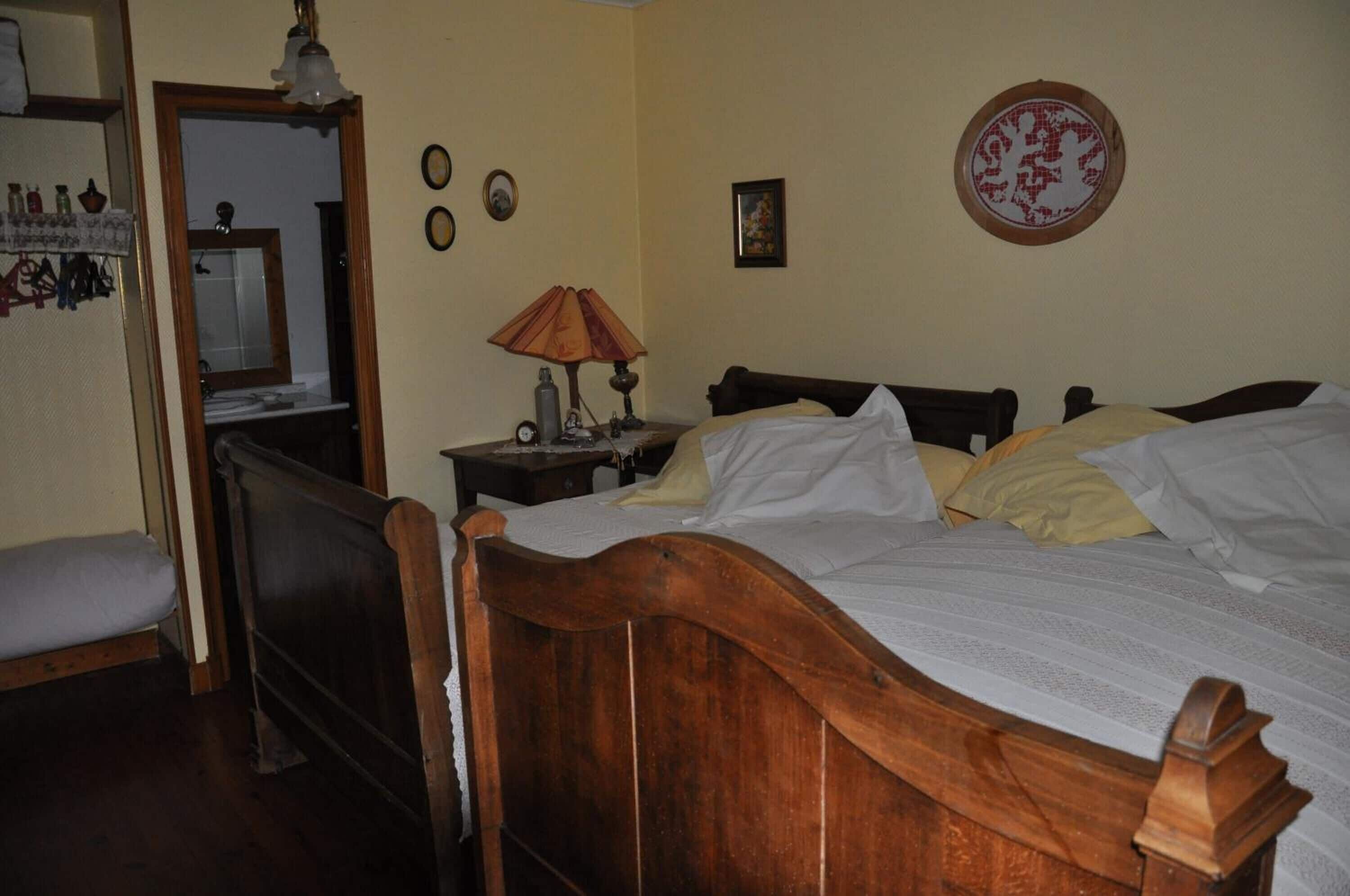 Un dormitorio con una cama de madera, una mesita de noche con una lámpara, un espejo y una pared decorada con cuadros.