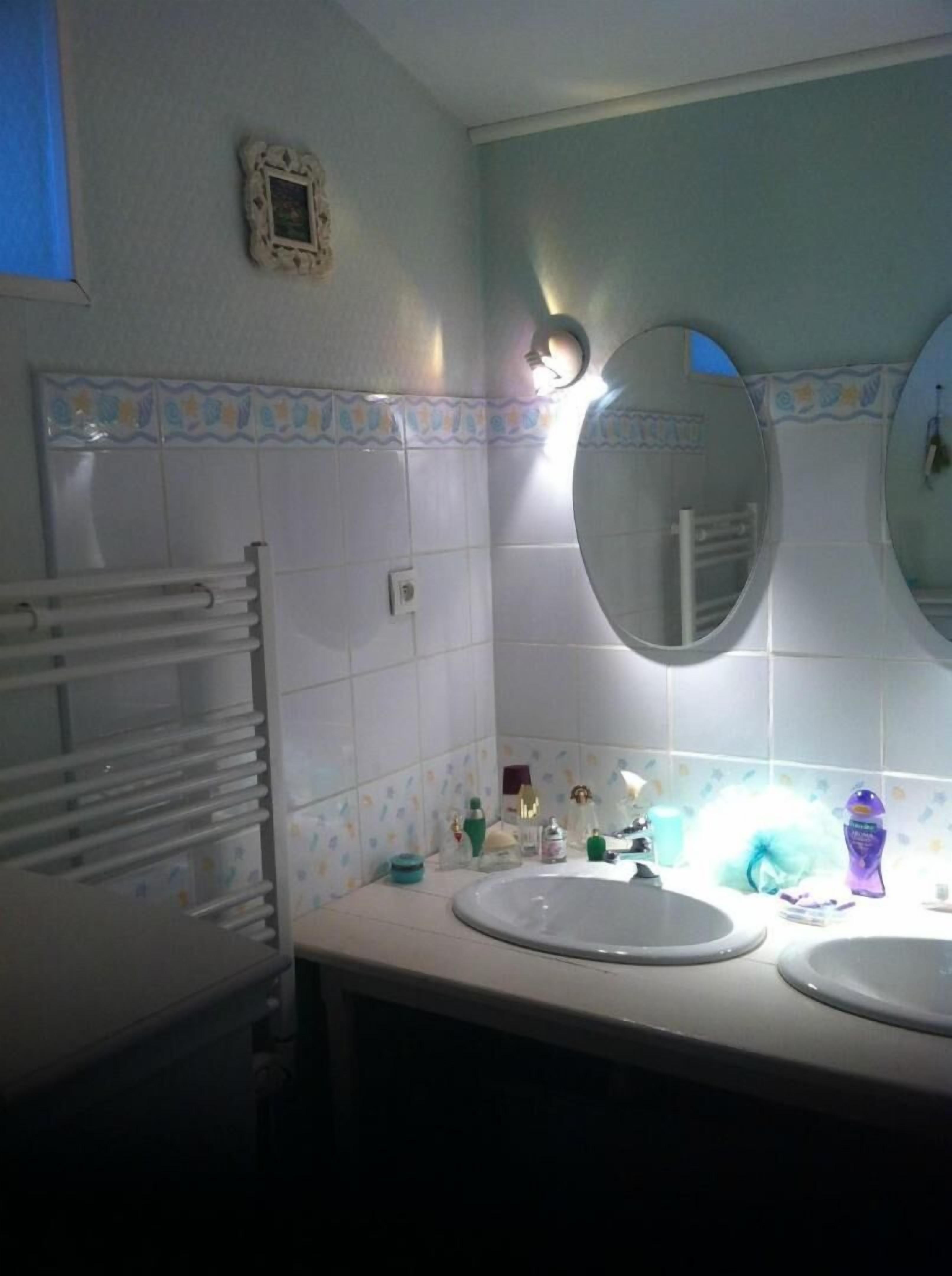 Un bagno con due lavandini, un portascopevoli e uno specchio.