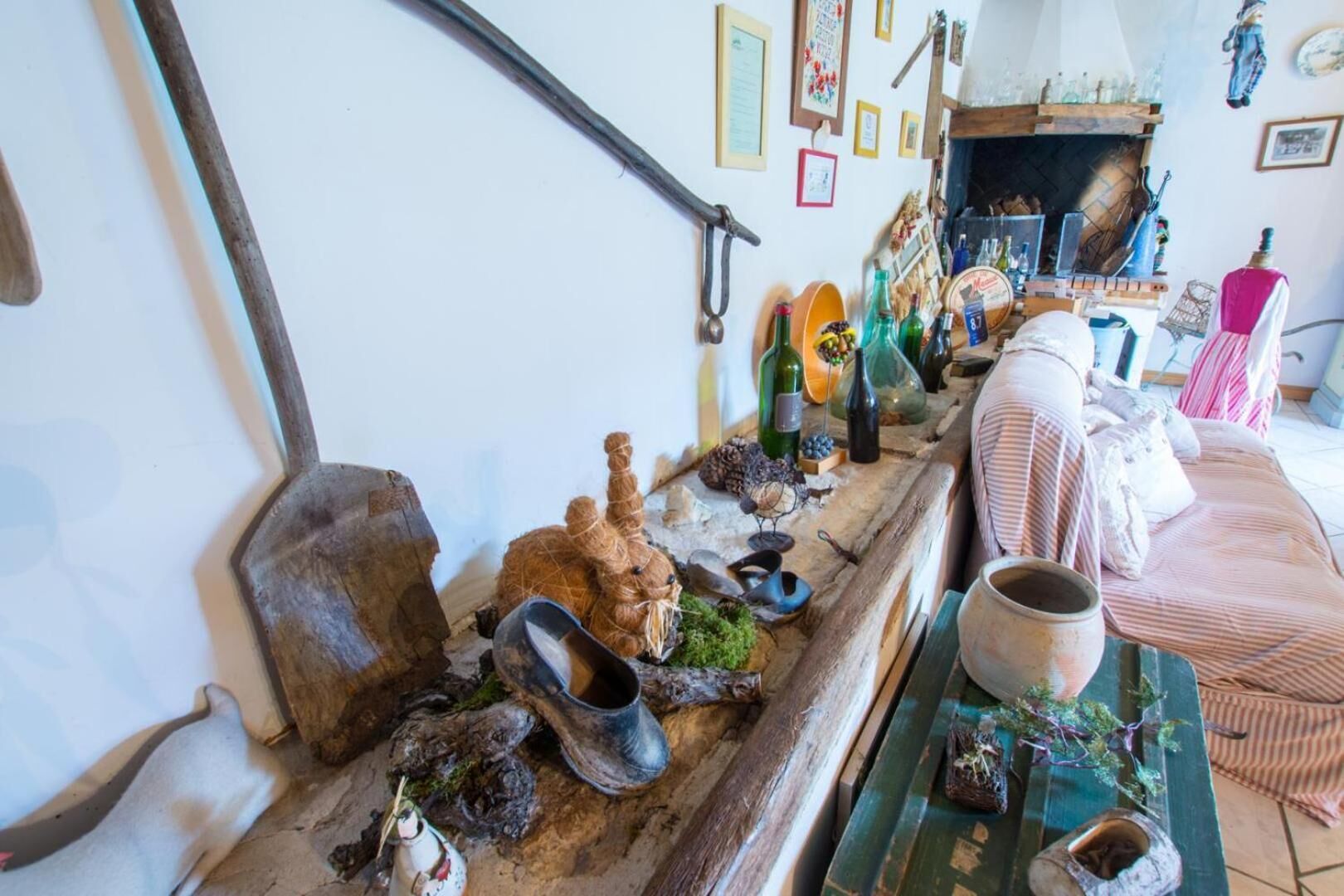 A rustic interior with a wooden table displaying various items, a sofa, and a fireplace.