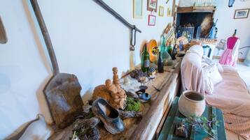 A rustic interior with a wooden table displaying various items, a sofa, and a fireplace.