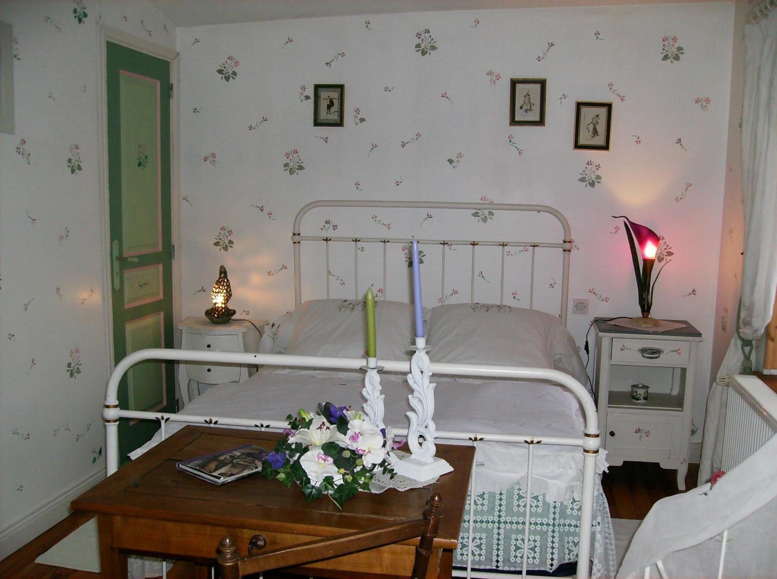 Een slaapkamer met een bed, nachtkastje en lamp.