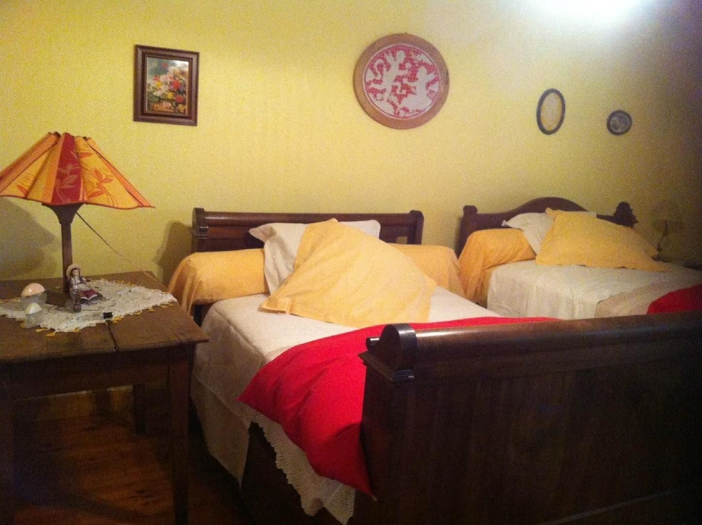A bedroom with two single beds, a nightstand with a lamp, and a small table with a decorative item.
