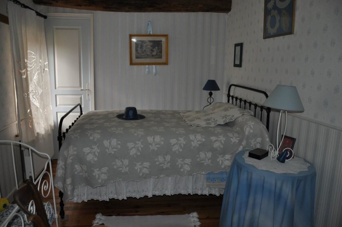 A bedroom with a bed, a bedside table with a lamp, a chair, and a door.