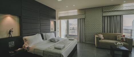 A modern hotel room with a large bed, a sofa, and a view of the city.