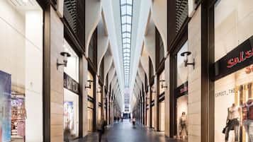 A corridor with high ceilings and skylights, lined with shops on both sides.