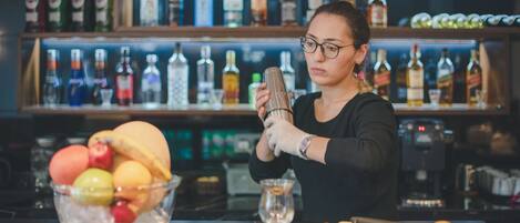 Un bartender preparando una bebida en la barra, con una variedad de botellas al fondo.