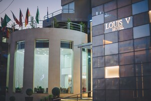 El exterior del Hotel Louis V, con un diseño moderno, ventanas grandes y un letrero llamativo.