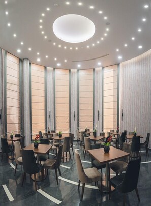 Enjoy dining in a stylish space with a circular light fixture, textured panels, and comfortable seating for groups.