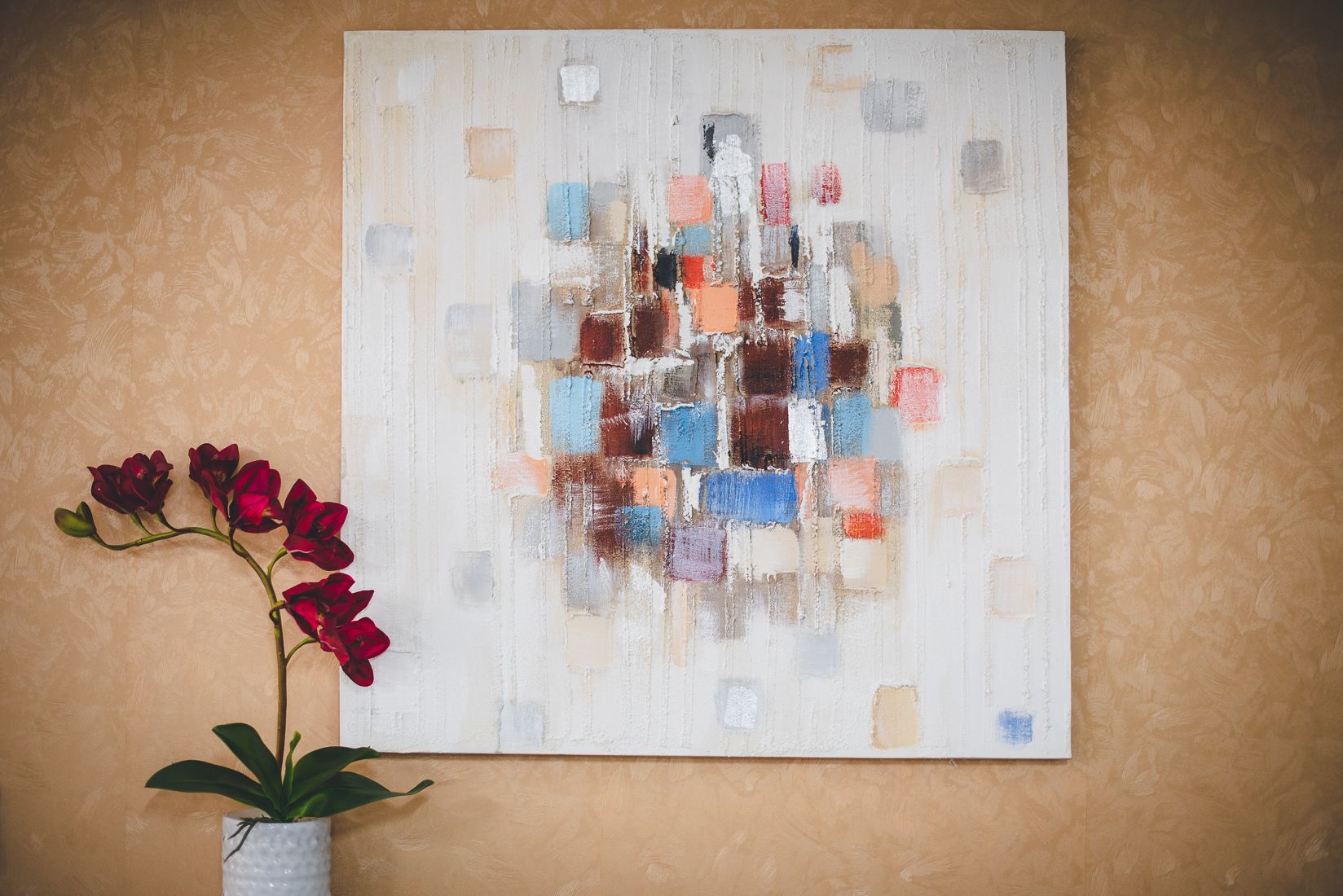 A painting with abstract shapes and a potted plant with red flowers.