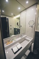 Un baño moderno con un espejo grande, dos lavamanos y una zona de ducha.