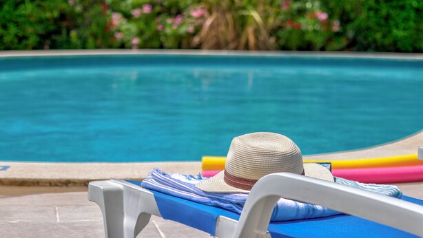 A poolside lounge chair with a straw hat, a blue towel, and colorful pool toys. - Apartamentos Llevant Puerto de Pollensa (Pollenca)
