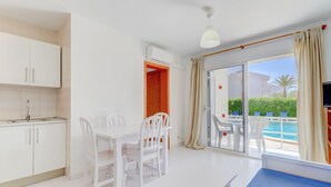 A modern hotel room with a kitchen, dining area, and a balcony with a pool view. - Apartamentos Llevant Puerto de Pollensa (Pollenca)