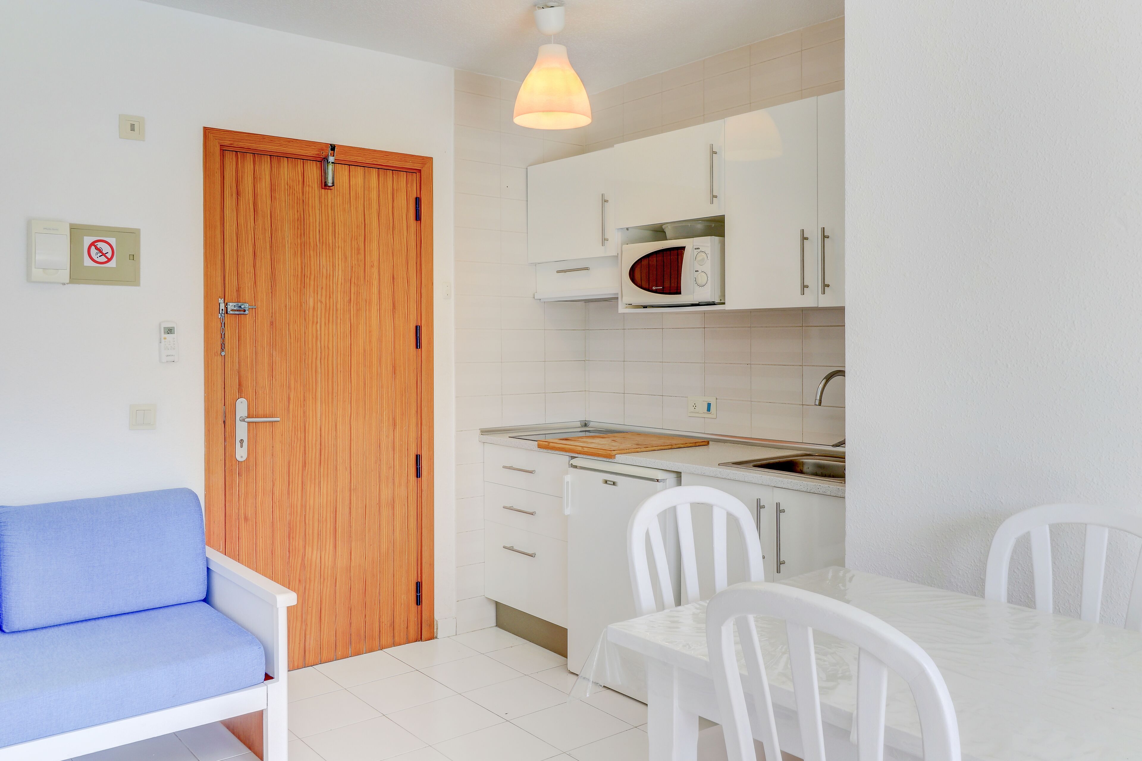 Una cocina compacta con armarios blancos, un microondas y una puerta de madera.