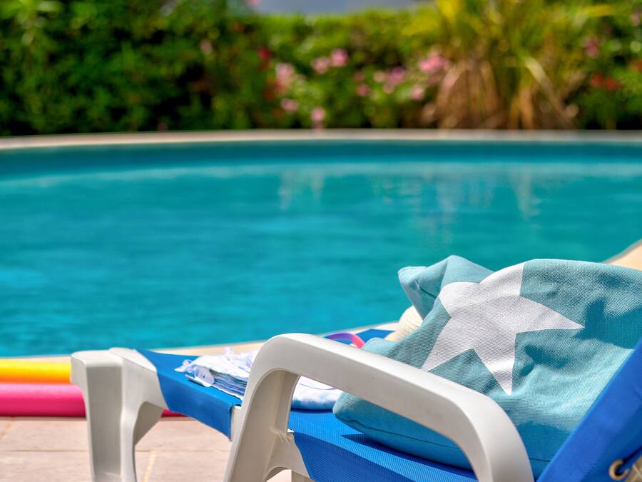A poolside area with a lounge chair and a pool.