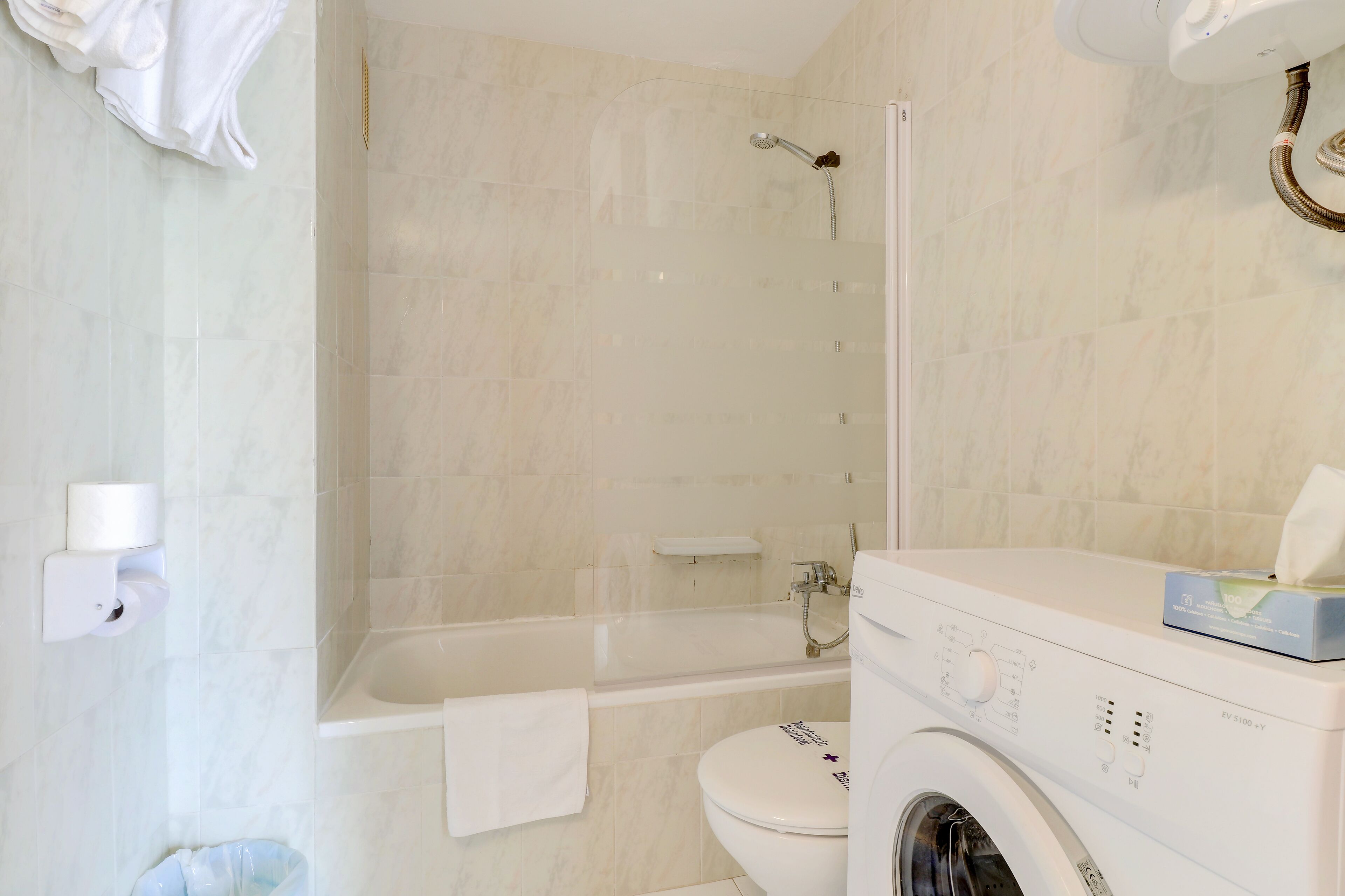 Een moderne badkamer met een badkuip, toilet en wasmachine.