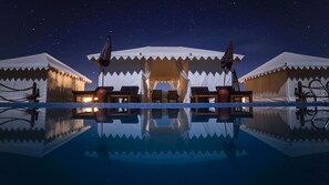 A nighttime view of a resort with a reflective pool, tents, and a clear starry sky. - Dhora Desert Resort & Spa By Eight Continents (Balesar)