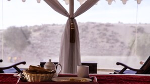 Een eettafel met een broodmand, een theepot, een kopje en een bord met eten.