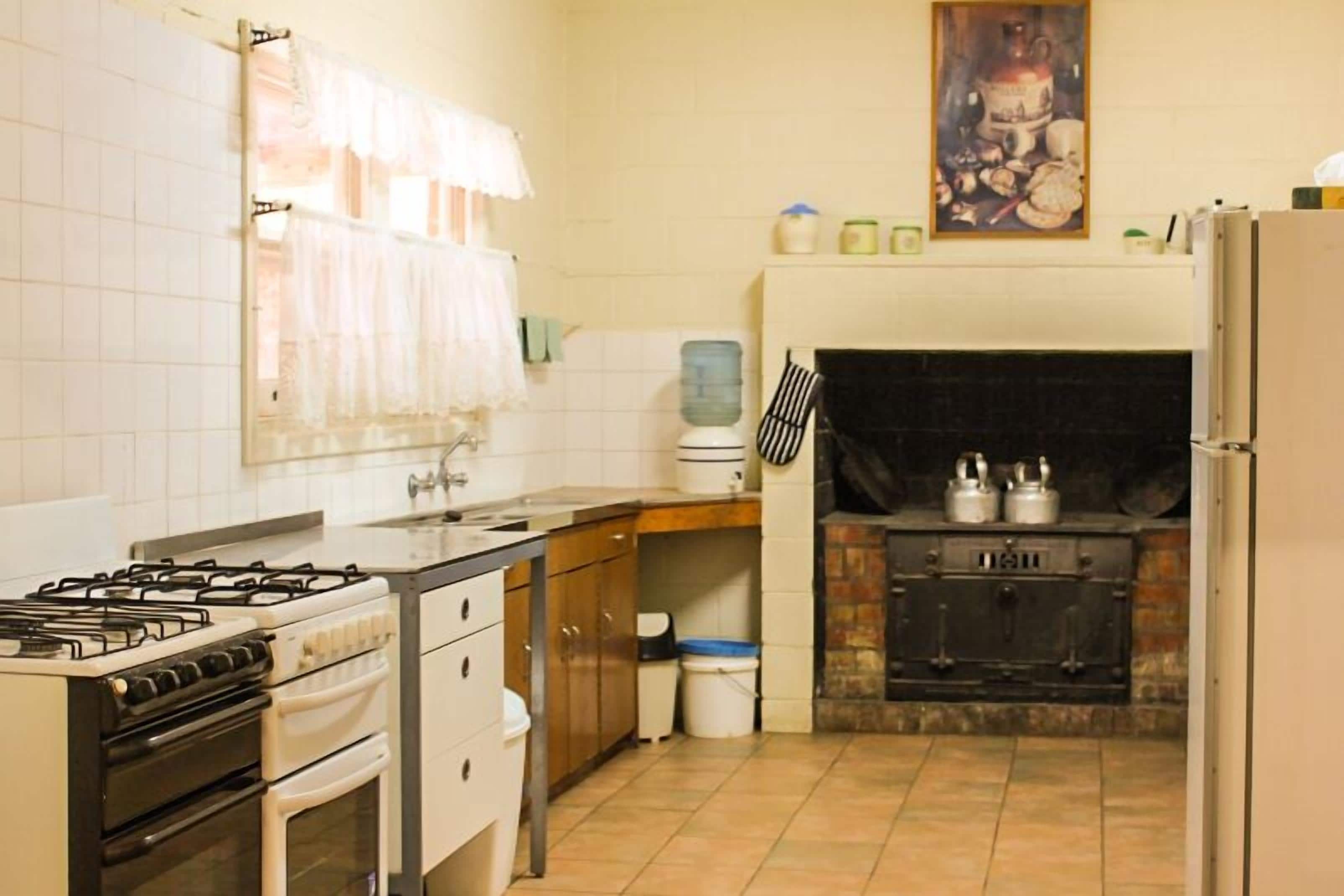 A kitchen with a gas stove, oven, sink, and a built-in fireplace.