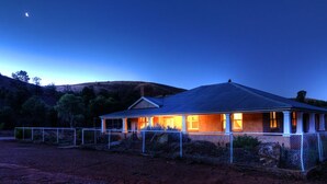 A house with a porch, a fenced yard, and a hilly landscape in the background. - Skytrek Willow Springs Station (Flinders Ranges)
