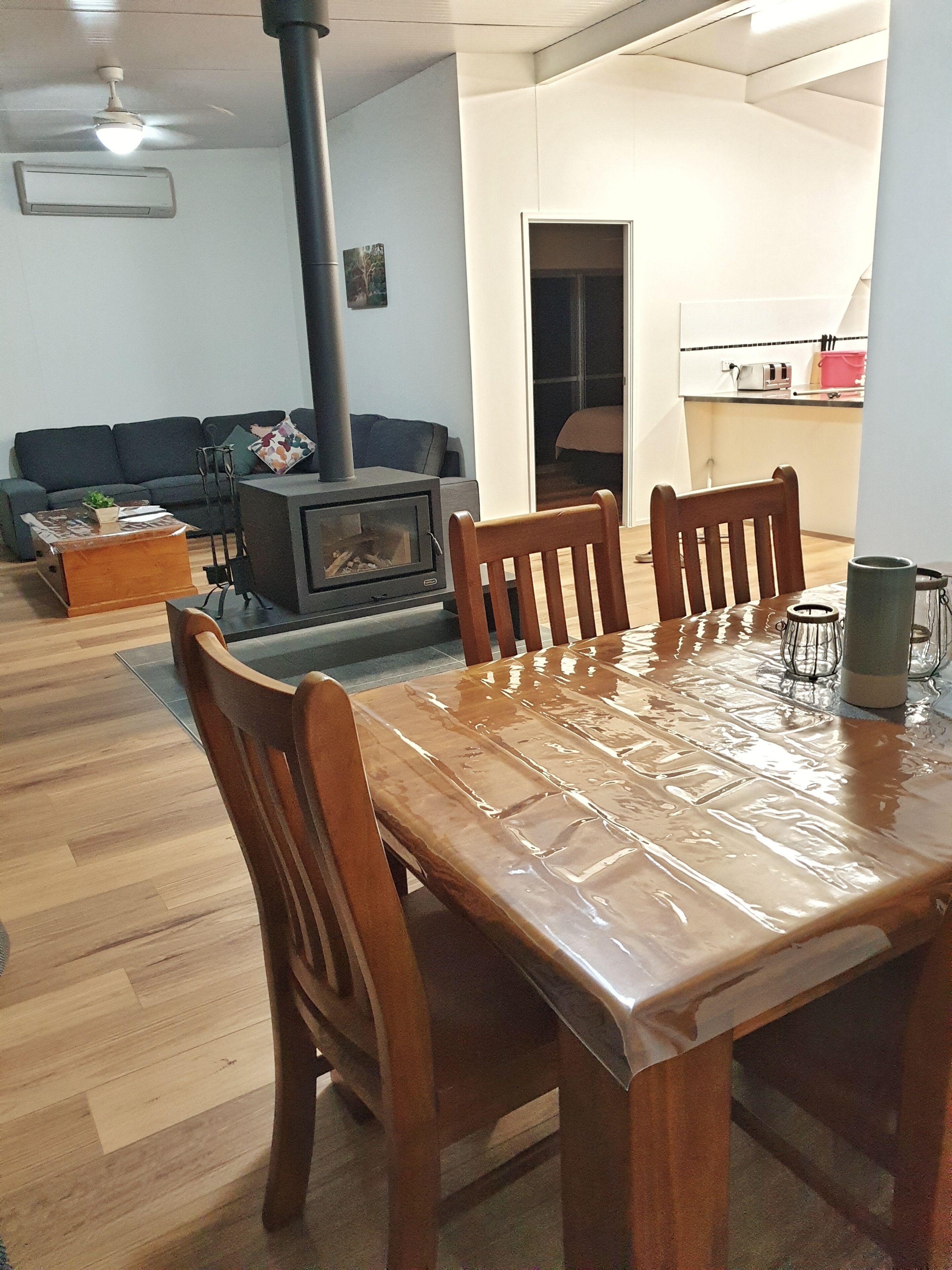 Een woonkamer met een houten eettafel, stoelen, een bank en een open haard.